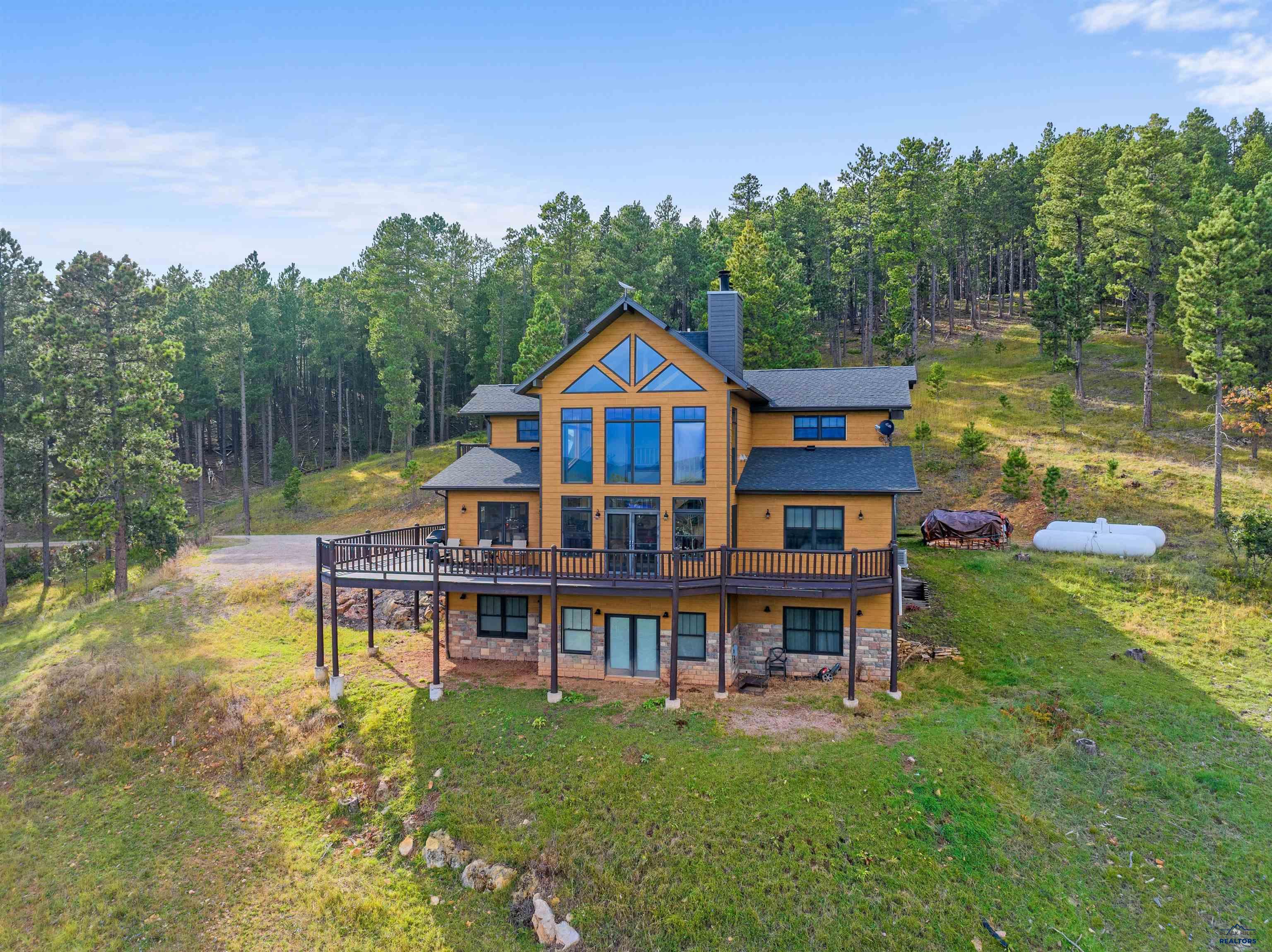 If privacy with a view is what you are looking for then this 9+ acre oasis just 3 miles away from historic downtown Deadwood is for you! This 3-story home boasts 5 bedrooms/3 bathrooms and is free from any restrictive covenants or HOA regulations. Enjoy the spacious 32x72 shop that can hold all of your summer and winter vehicles. If you own horses this property is perfect with the horse stalls already in the shop. With its expansive 4,150 square feet of living space, this captivating property offers the perfect blend of tranquility and luxury. The large windows frame panoramic views, inviting the outside in and bathing the living spaces with an abundance of natural light. For nature enthusiasts, the property's border with the forest service ensures direct access to the beauty of the outdoors. Don't miss the chance to make this mountain retreat your own and experience the beauty and tranquility it has to offer. Call Dylon Vasknetz with The Real Estate Center of Sturgis (605) 490-0588!