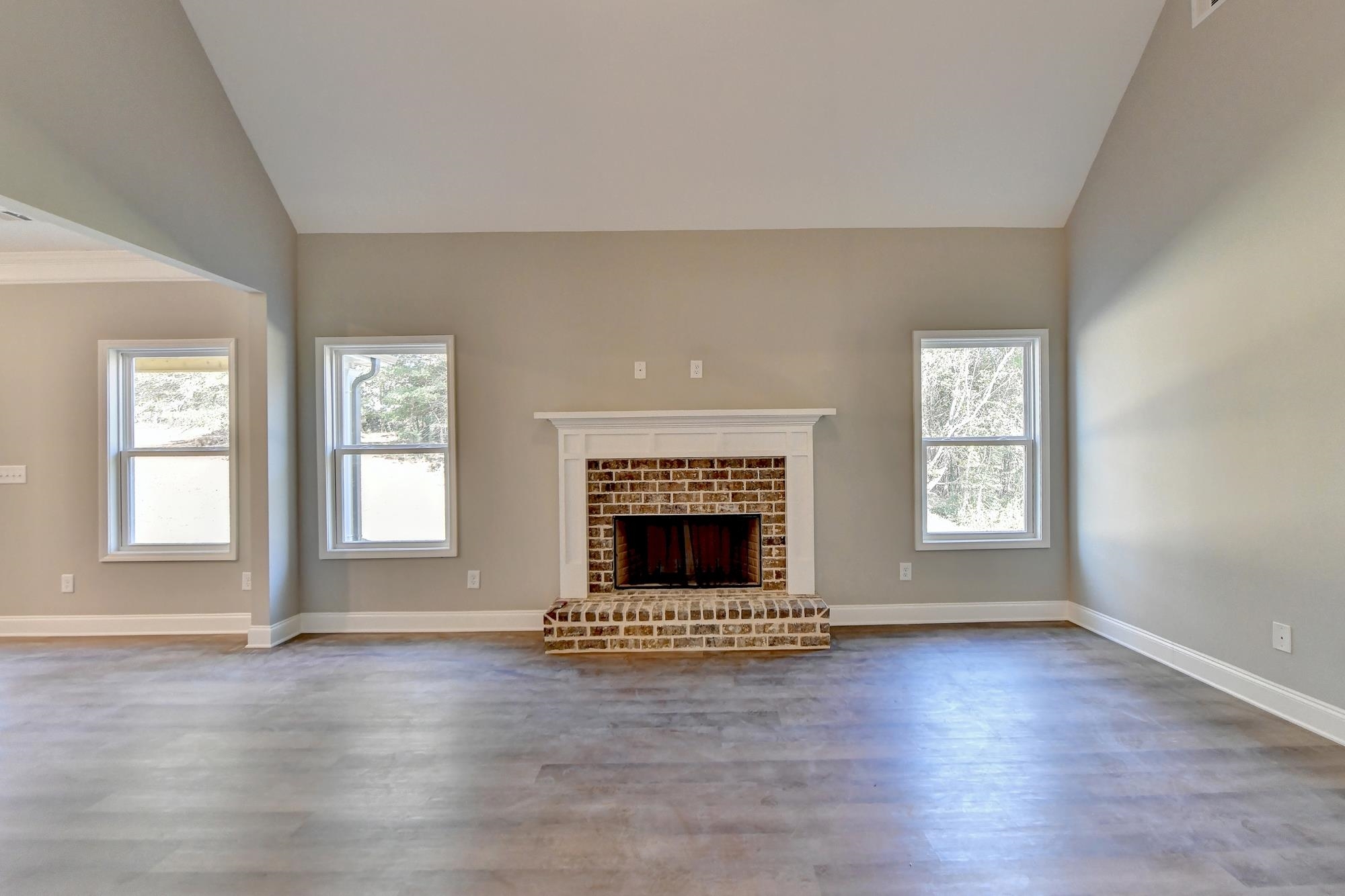 Family room featuring high vaulted ceiling, light wood-type flooring, ceiling fan, and a fireplace