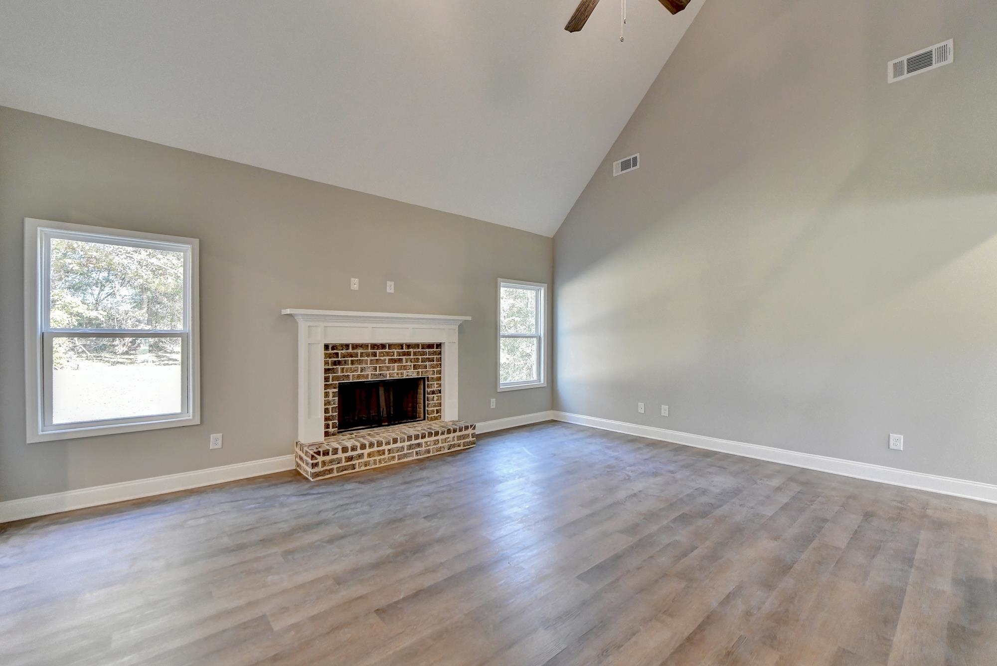 Family room featuring high vaulted ceiling, light wood-type flooring, ceiling fan, and a fireplace