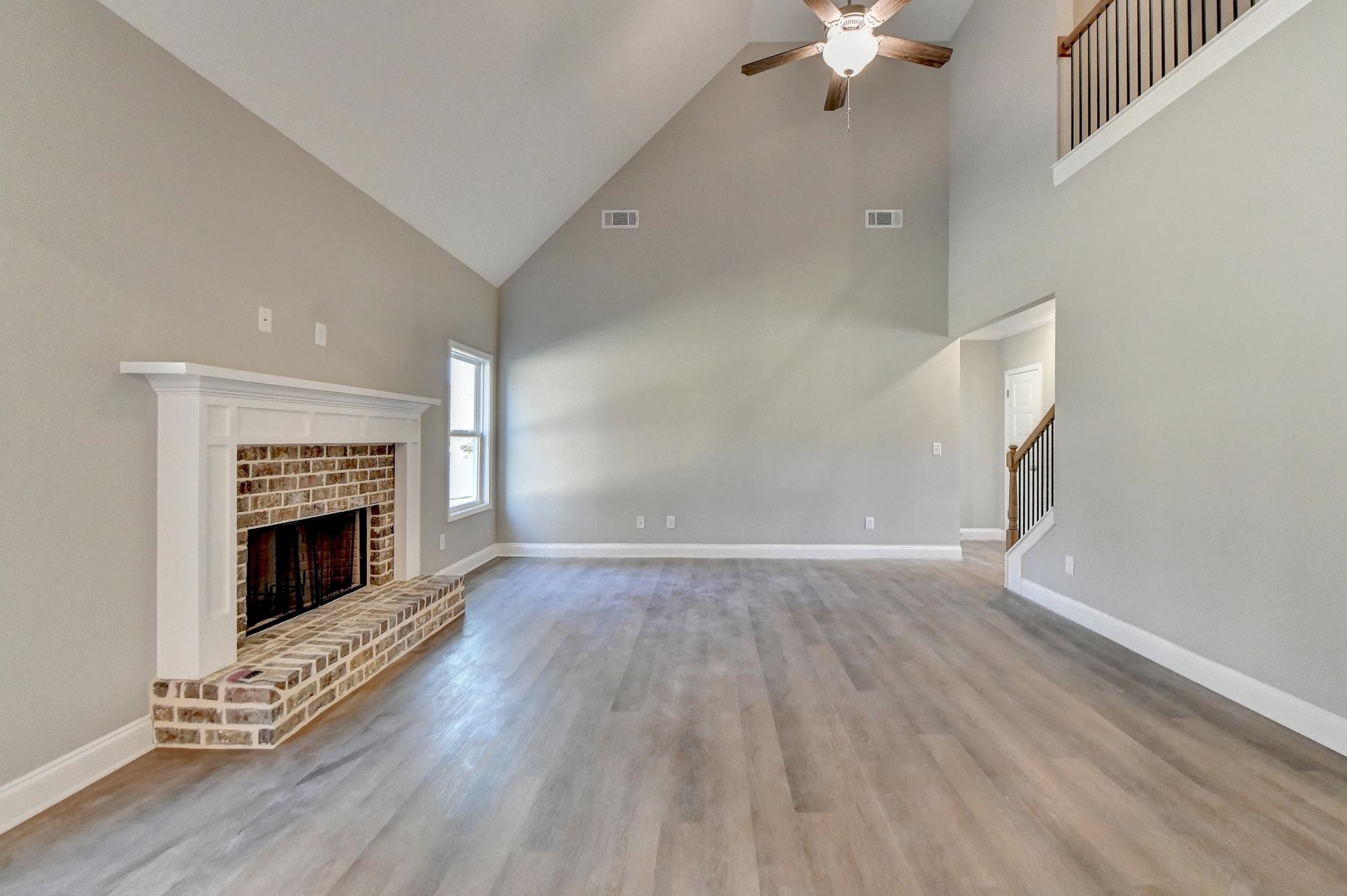 Family room featuring high vaulted ceiling, light wood-type flooring, ceiling fan, and a fireplace