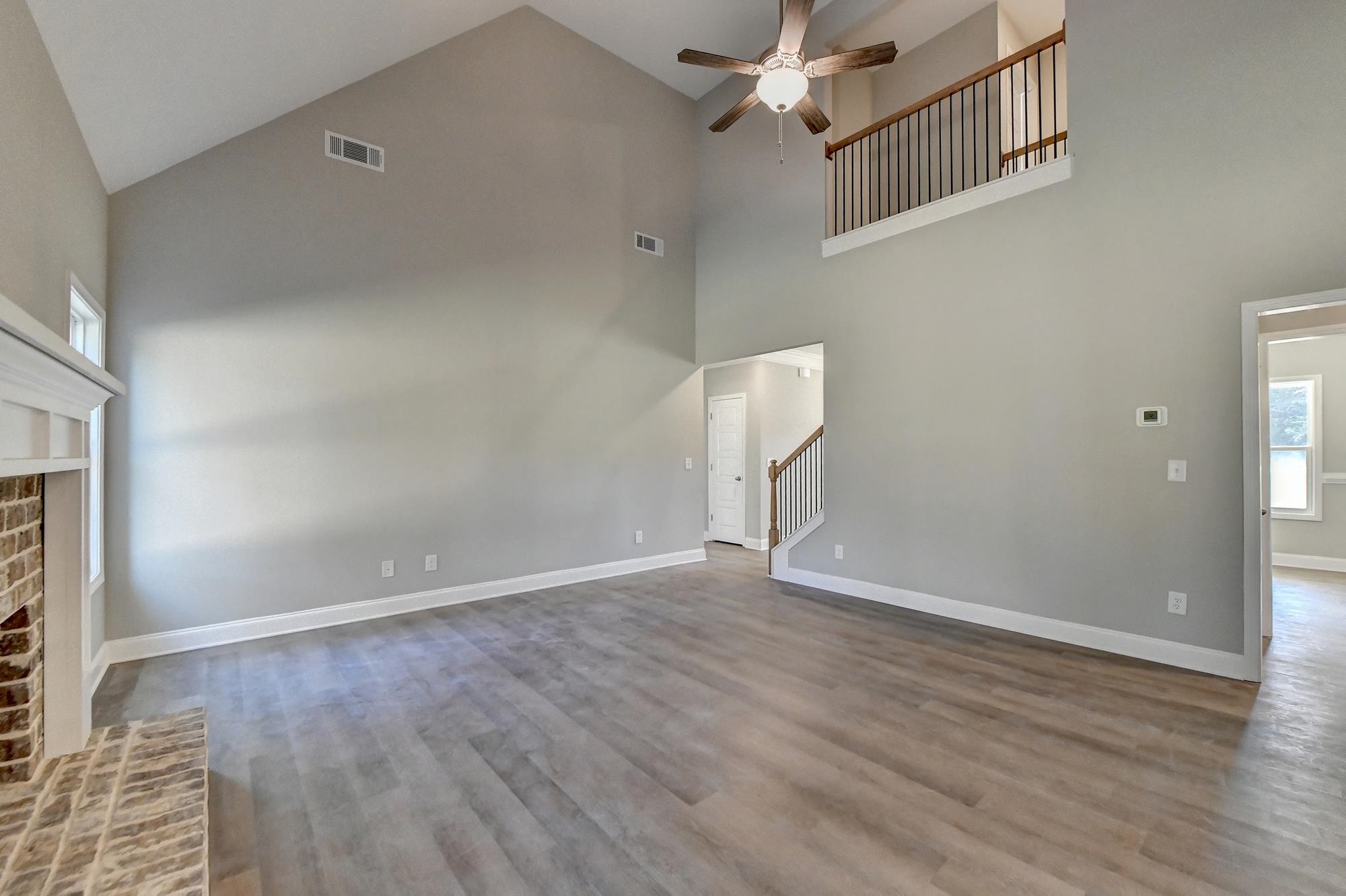 Family room featuring high vaulted ceiling, light wood-type flooring, ceiling fan, and a fireplace