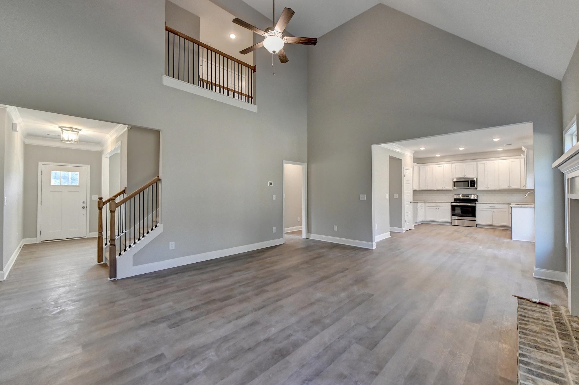 Family room featuring high vaulted ceiling, light wood-type flooring, ceiling fan, and a fireplace