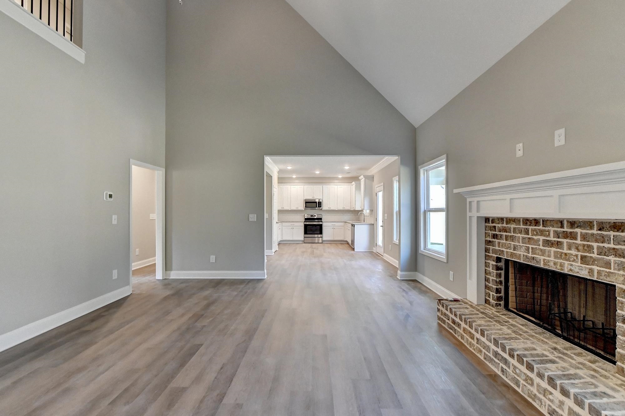 Family room featuring high vaulted ceiling, light wood-type flooring, ceiling fan, and a fireplace