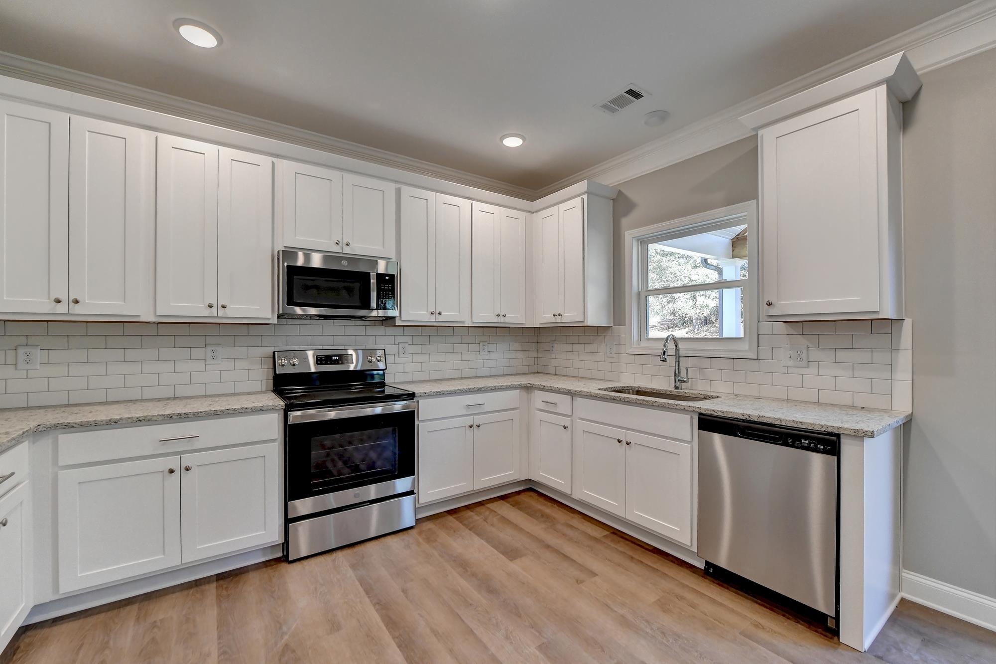 Kitchen with sink, crown molding, light hardwood / wood-style floors, stainless steel appliances, an