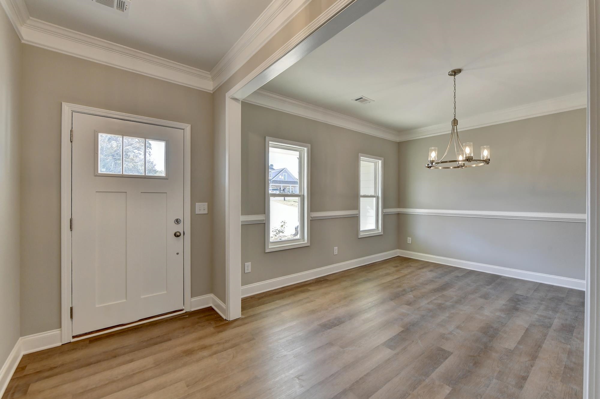 Entrance foyer with a notable chandelier, crown molding, and light hardwood / wood-style floors