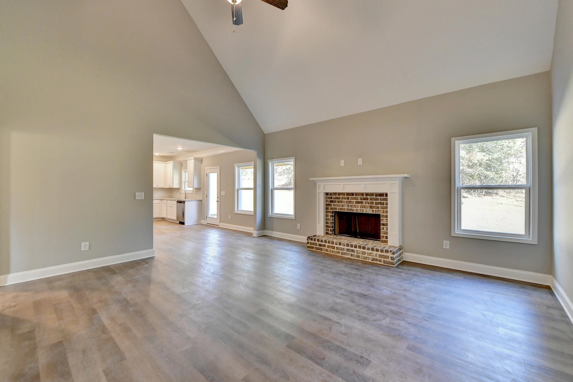 Family room featuring high vaulted ceiling, light wood-type flooring, ceiling fan, and a fireplace