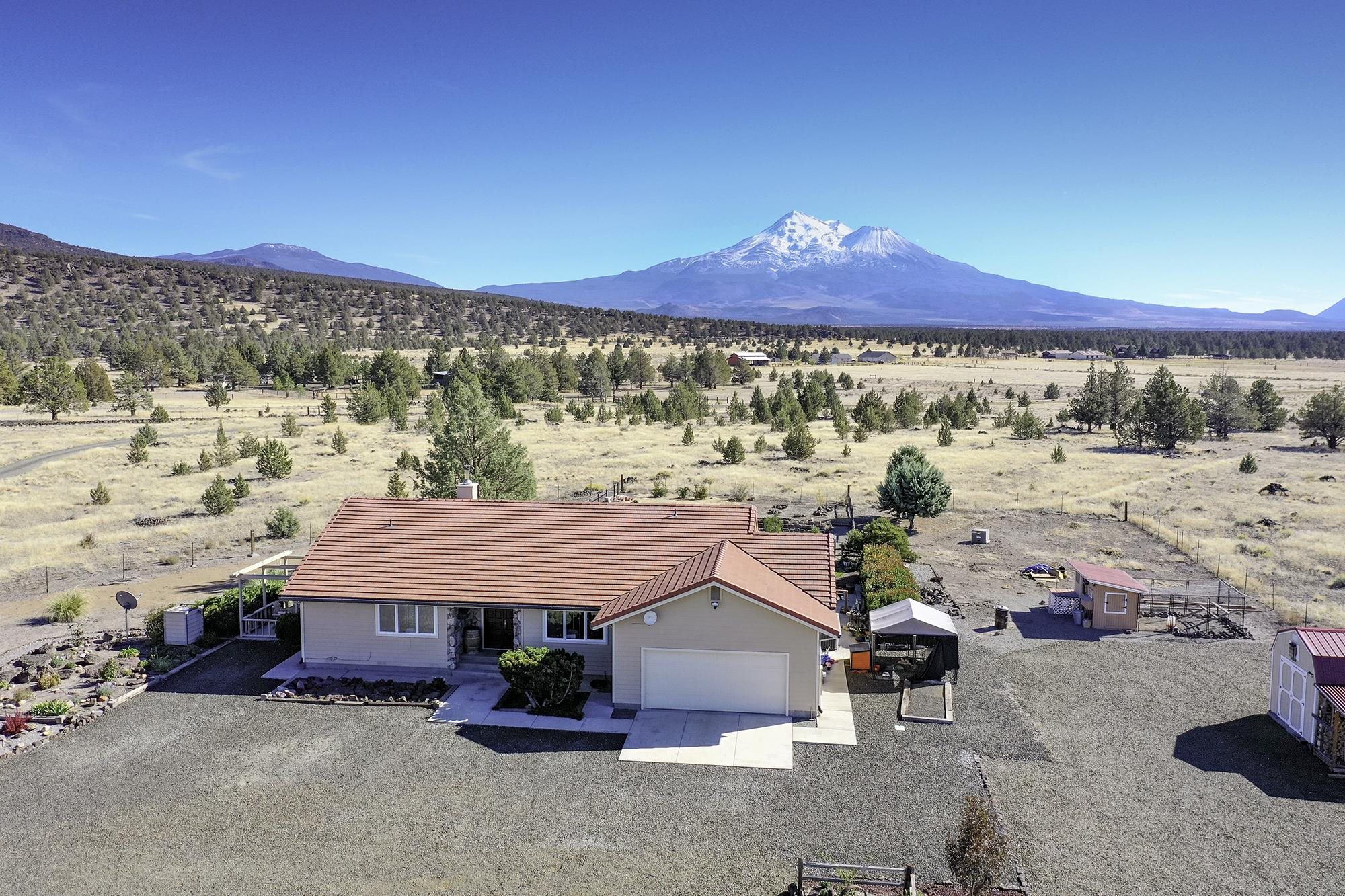 Breathtaking views of Mt. Shasta from this nicely situated 3 bed/ 2 bath home. Quiet setting with home set off the road. Walk into a large entry and through to the living room with stunning views. Dining room open to both living room and updated kitchen with luxurious stainless steel appliances. Master suite has doors to the back patio, 2 closets, and updated bathroom. Both guest bedrooms are a good size for closet storage. The home boasts a large laundry/ mud room between the kitchen and attached garage. Plenty of elbow room on this large property over 54 acres. Additional detached garage/ work shop along with large metal covered parking with side covered area as well. Driveway and areas around buildings are nicely graveled. Several additional out buildings/ sheds for storage. A rare find!