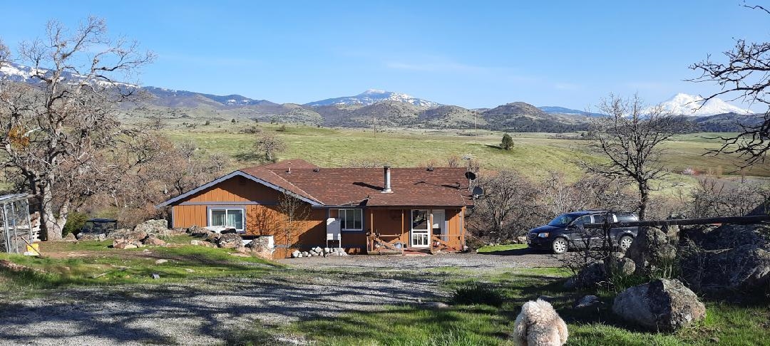 Nestled on the edge of a breathtaking landscape, this 2,400 square-foot home 3 bedroom 2 bath home offers an unparalleled connection to nature with stunning views of Mt. Shasta and the surrounding valleys. The great room takes full advantage of its setting, with large windows framing panoramic vistas that stretch across the valleys and up to the towering peak of Mt. Shasta. Whether you’re lounging in the spacious living room or enjoying a meal in the dining area, the majestic mountain serves as a constant, awe-inspiring backdrop. Imagine 250 acres of serene, rolling land, offering expansive views in every direction. The terrain is varied, with lush meadows and gentle hills that create a natural landscape of beauty and tranquility. As you explore, the land slopes down toward the banks of a peaceful creek, its waters flowing gently along the property’s edge. The creek provides not only a soothing backdrop but also a rich habitat for local wildlife. There is a large shop for all your projects as well as a 2 car garage and small horse barn . Most of the property is fenced and cross fenced. All information is approximate and subject to change