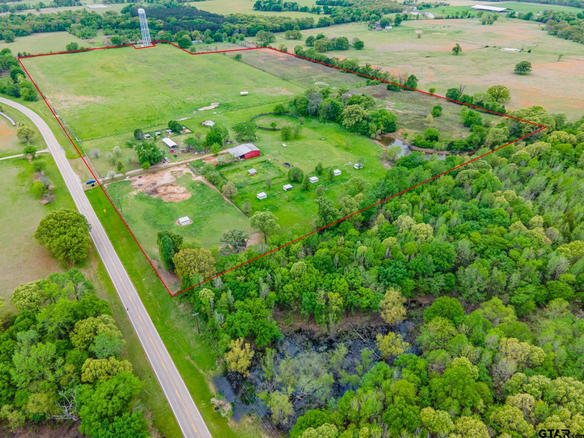 Bring your horses and your dogs! This 50 acre property features a 30 acre irrigated (needs some repair) hay meadow, an additional 8 acre fenced pen, as well as 6 loafing sheds fenced and cross fenced plus pens. A large barn with 2 additional horse or calf pens, 60' training ring and a 150' round arena. Pond stocked with bass, blue gill and catfish. Current use is for dog and horse breeding, only some chain link yards will remain. 3 bedroom 2 bath ranch style home in need of work or build a new home in its place! Road frontage on FM Road and County Road 2436.